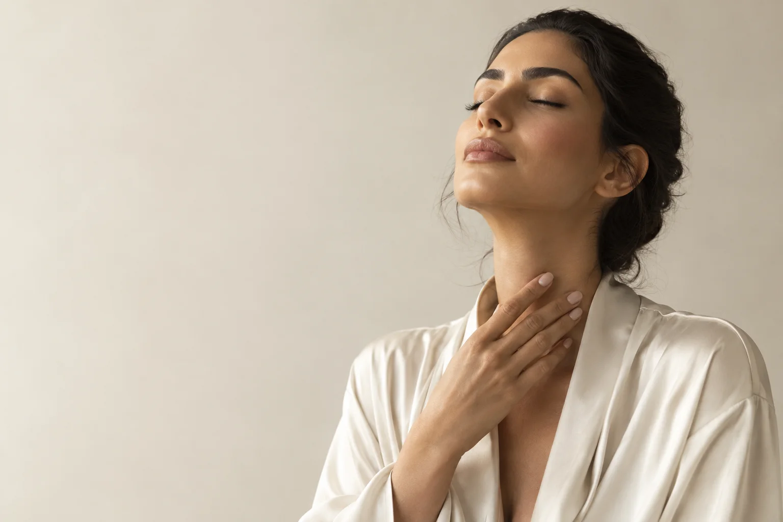 A woman at the moment of applying fragrance to her throat